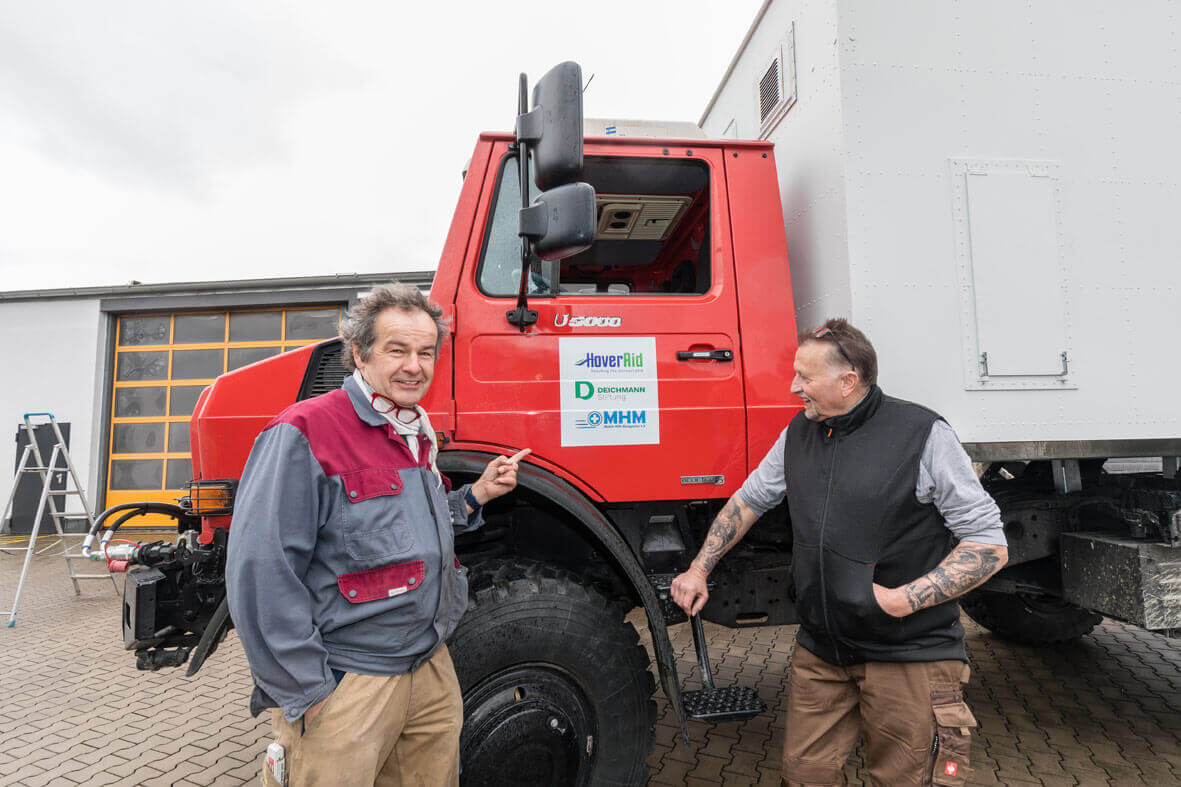 DEICHMANNn-Stiftung | Madagaskar-Mobile-Klinik – Max Westhoven und Gerd Burkart sind zwei von elf Ehrenamtlichen, die sich am Umbau von Containern und Trucks beteiligen Madagaskar-Mobile-Klinik – Zwei Männer posieren vor dem Führerhaus eines LKW